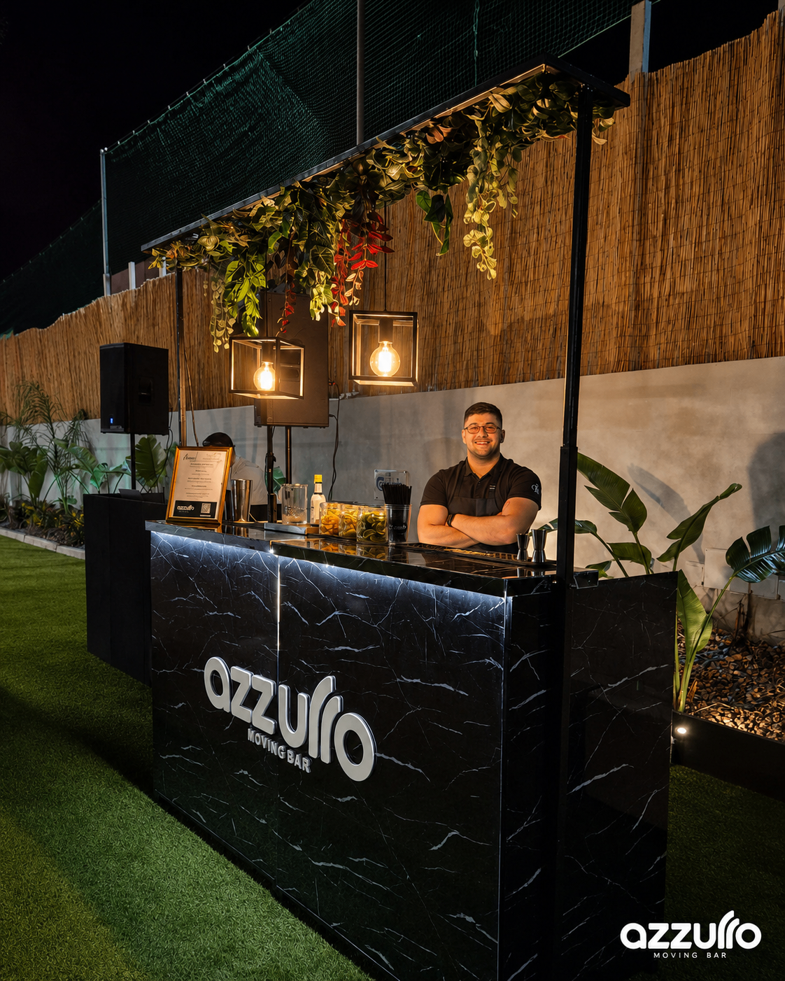 Azzurro Moving Bar bartender standing behind the black marble bar at night